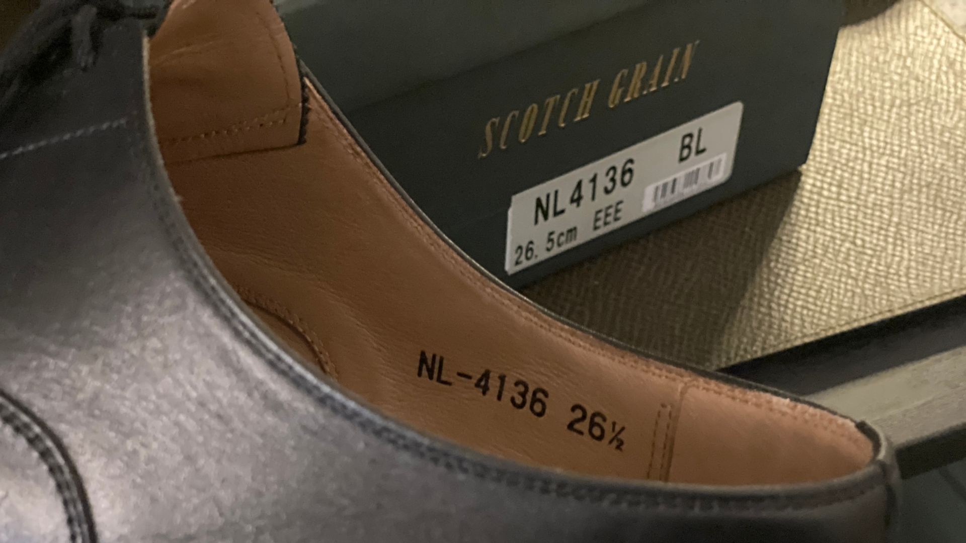 黒い革靴の内側にあるNL-4136・26½の刻印と、背後の靴箱ラベル